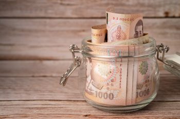 Thai baht banknotes in grass jar on wooden background, business saving finance investment concept.